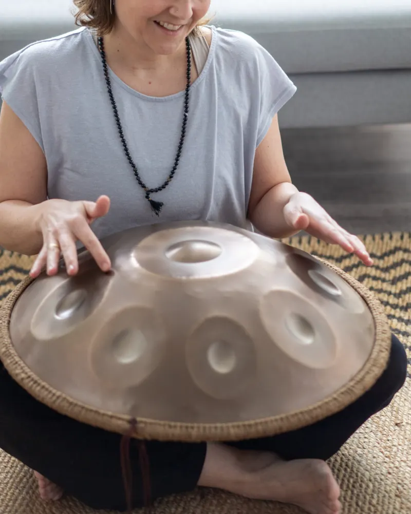 Lisa spielt eine Handpan, die auf ihrem Schoß liegt
