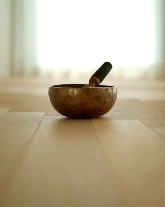 Eine Klangschale aus Bronze mit Schlägel auf einem Holzboden